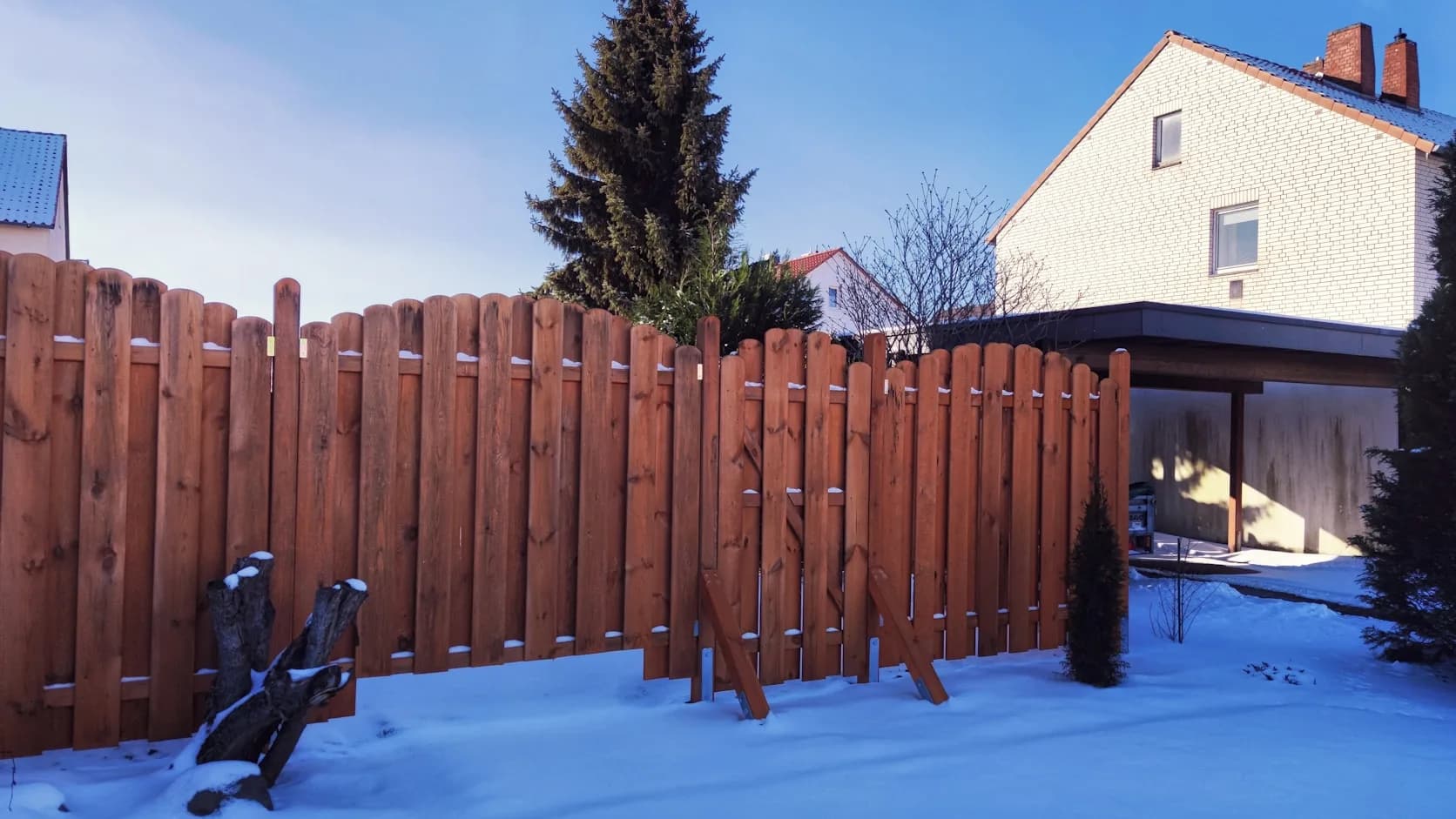 A finished wood privacy fence running along a residential backyard, the kind of fence a crew installs.