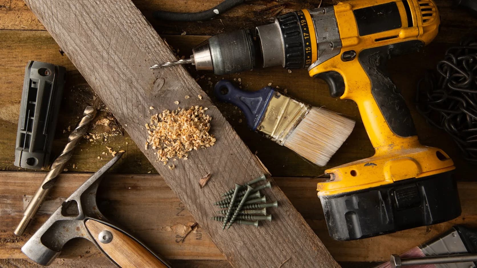 A handyman’s cordless drill and hand tools laid out on a workbench, ready for the job.