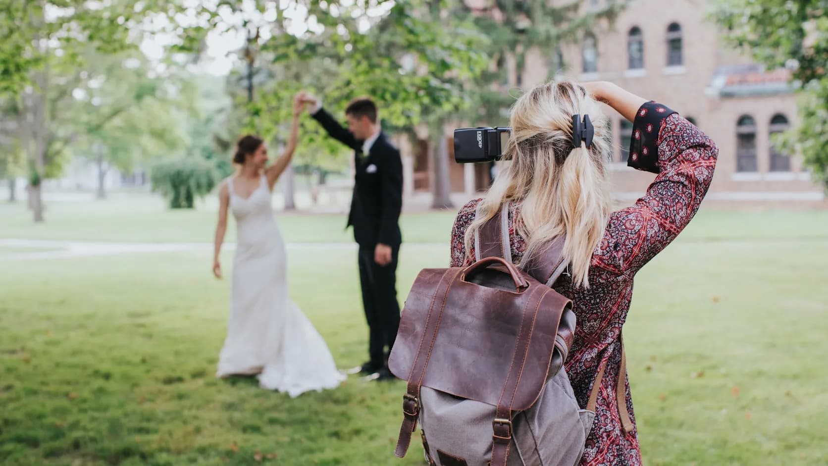 A wedding photographer at work shooting a couple outdoors